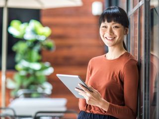 Asian woman smiling and holding a tablet