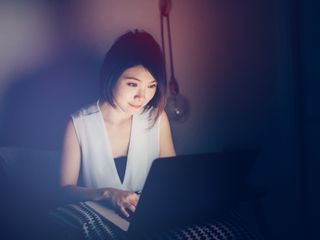 Asian woman using laptop on bed