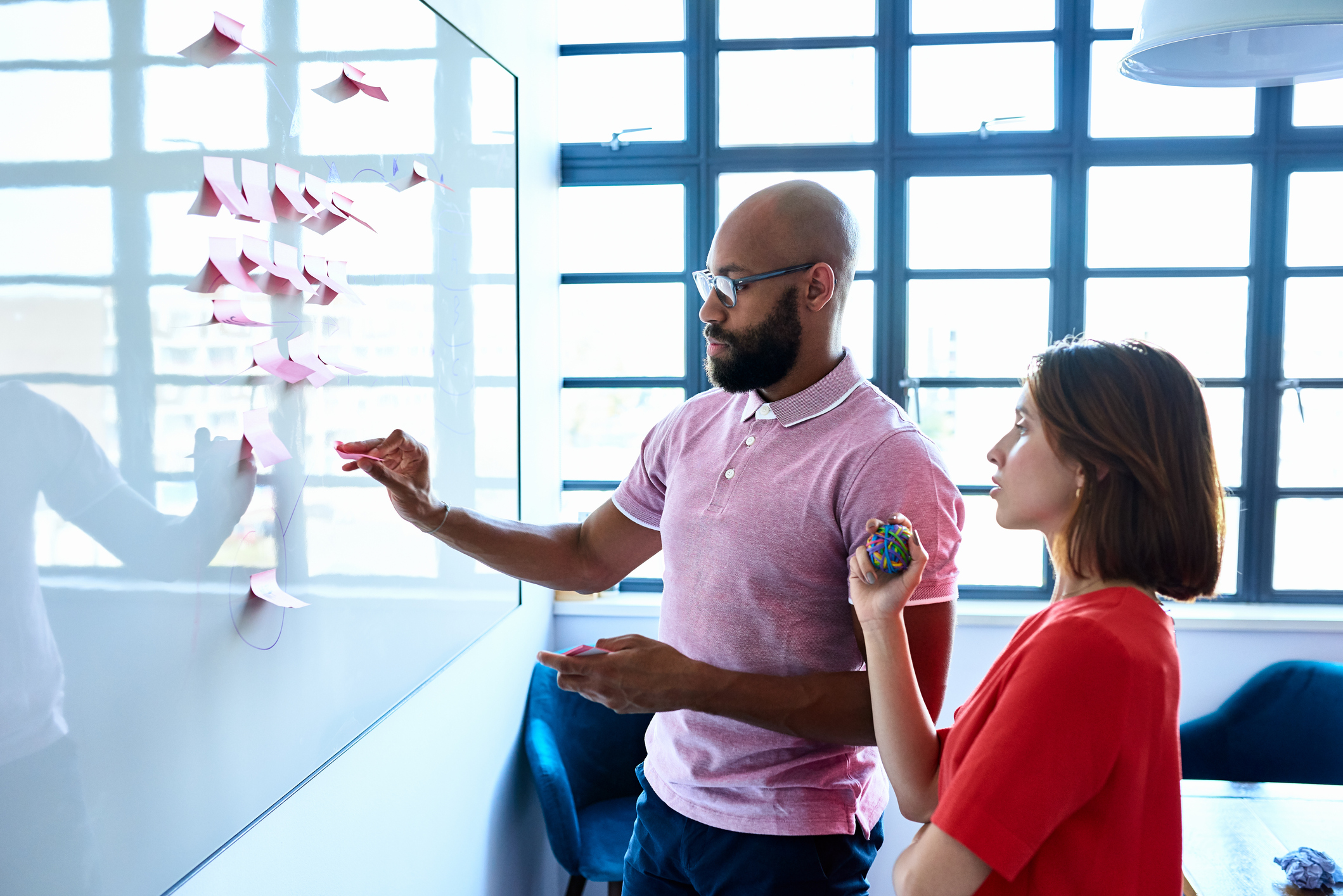 Black man and white woman planning with notes on whiteboard