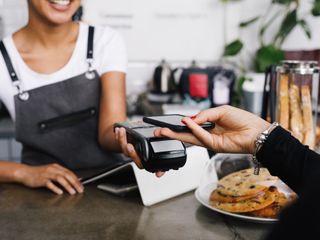 Customer using mobile phone for contactless payment at a cafe