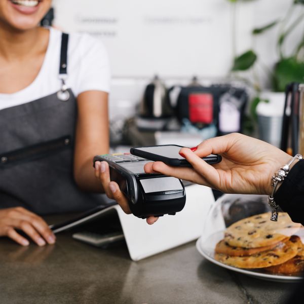 Customer using mobile phone for contactless payment at a cafe