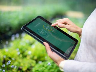 Gardener using digital tablet for information about new plants