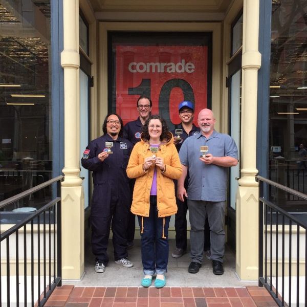 Group of 4 people holding trophies and the word "Comrade" in the backgroud