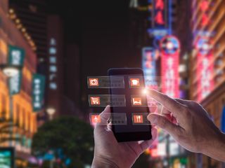 Hand holding smart phone using an AR application in the middle of a street at night