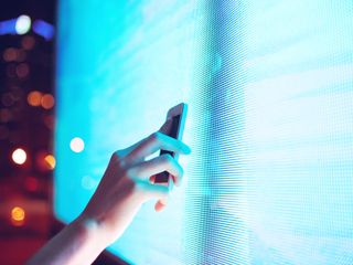 Hand placing smartphone near a screen