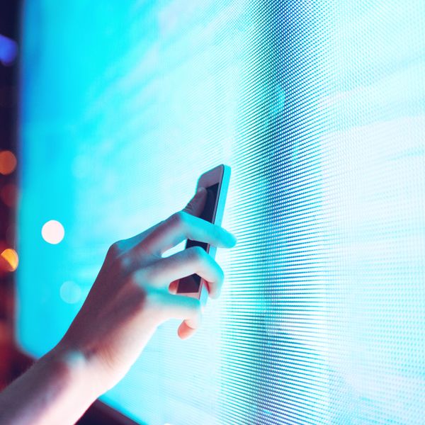 Hand placing smartphone near a screen