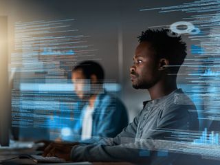 Male programmer working on a computer code at night