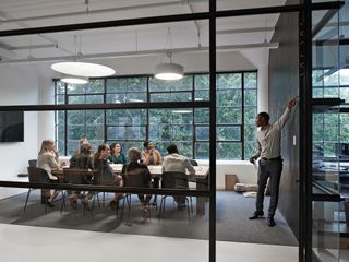 Man pointing and discussing while colleagues sitting in board room during office meeting