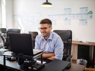 Man sitting at his desk smiling during a video call in office