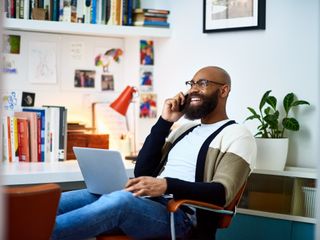 Man sitting on chair with laptop on phone call