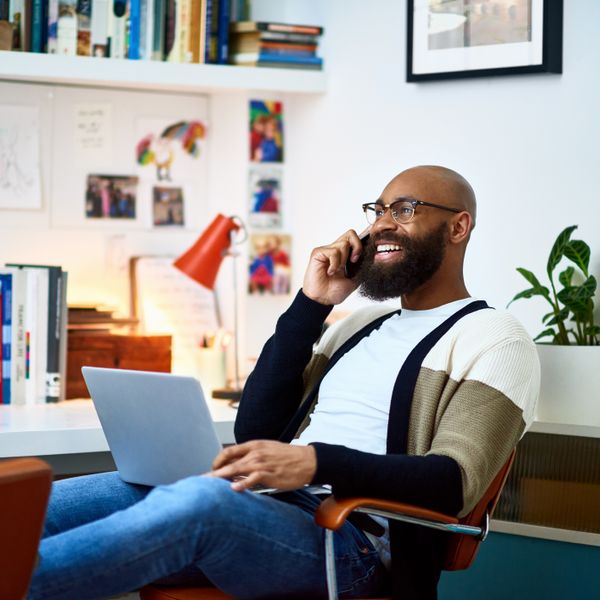 Man sitting on chair with laptop on phone call