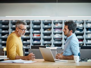 Men using laptop and discussing at desk