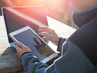 Person at daylight with smartphone and computer