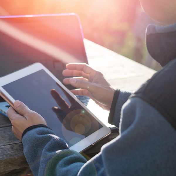 Person at daylight with smartphone and computer