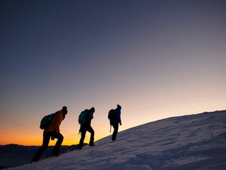 Three persons in cold winter day moving up on the snowy mountains