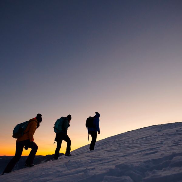 Three persons in cold winter day moving up on the snowy mountains