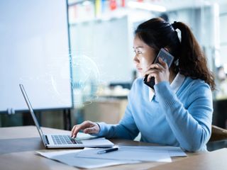 Woman using mobile phone on virtual visual screen of globe in modern office