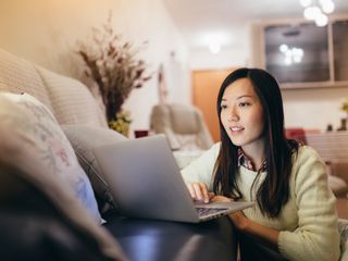 Woman working on laptop by the sofa in living room
