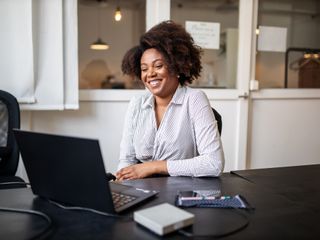 Woman sitting in office smiling during a video call