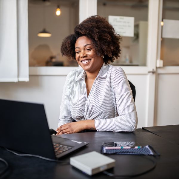 Woman sitting in office smiling during a video call