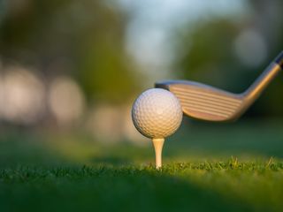 Golf ball on green grass ready to be struck on golf course 