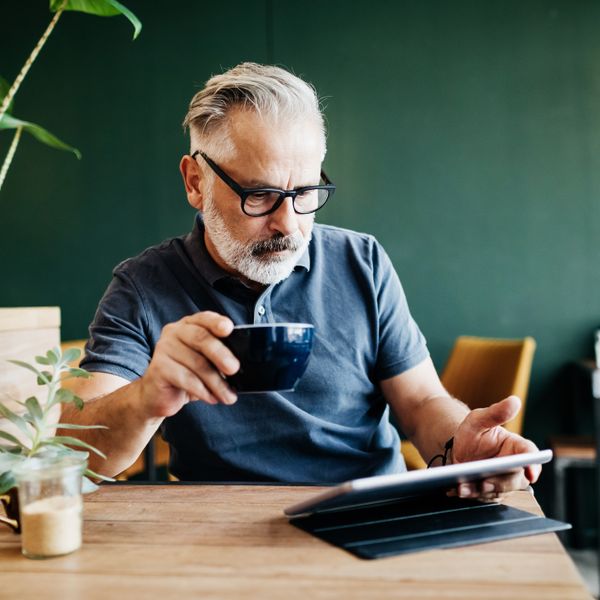 Man drinking a coffee while using a tablet