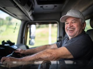 Truck driver sitting in cab and smiling to the camera