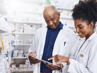 Two pharmacists doing inventory in a pharmacy with a digital tablet
