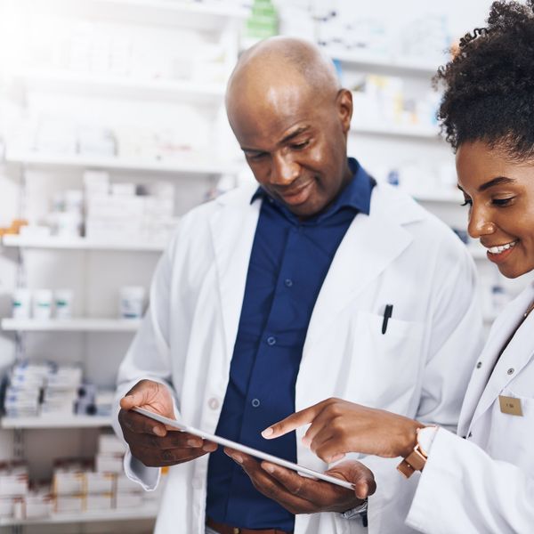 Two pharmacists doing inventory in a pharmacy with a digital tablet