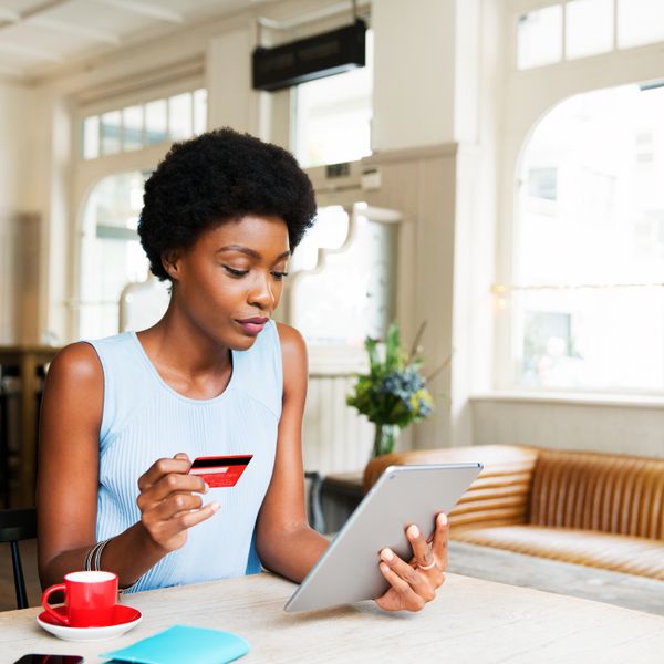Woman holding a credit card and a tablet