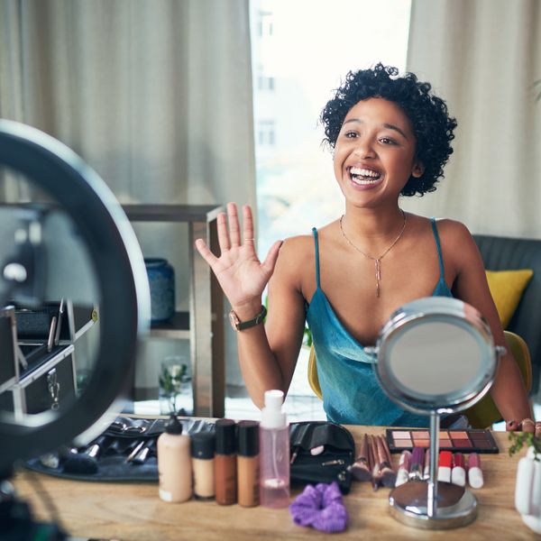 A woman doing a makeup tutorial in front of a light ring and camera