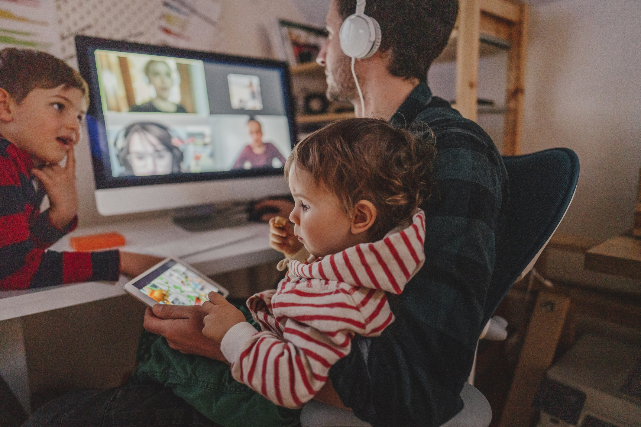 Man having video conference at home with his children around