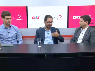 Tr&ecirc;s homens sentados em frente a um balc&atilde;o de entrevista conversando
