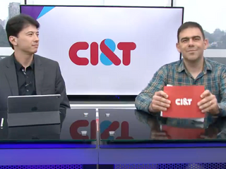 Dois homens sentados em frente a um balc&atilde;o de entrevista