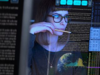 Woman holding a pencil with codes reflected on her