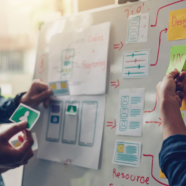 two people putting notes on the wall