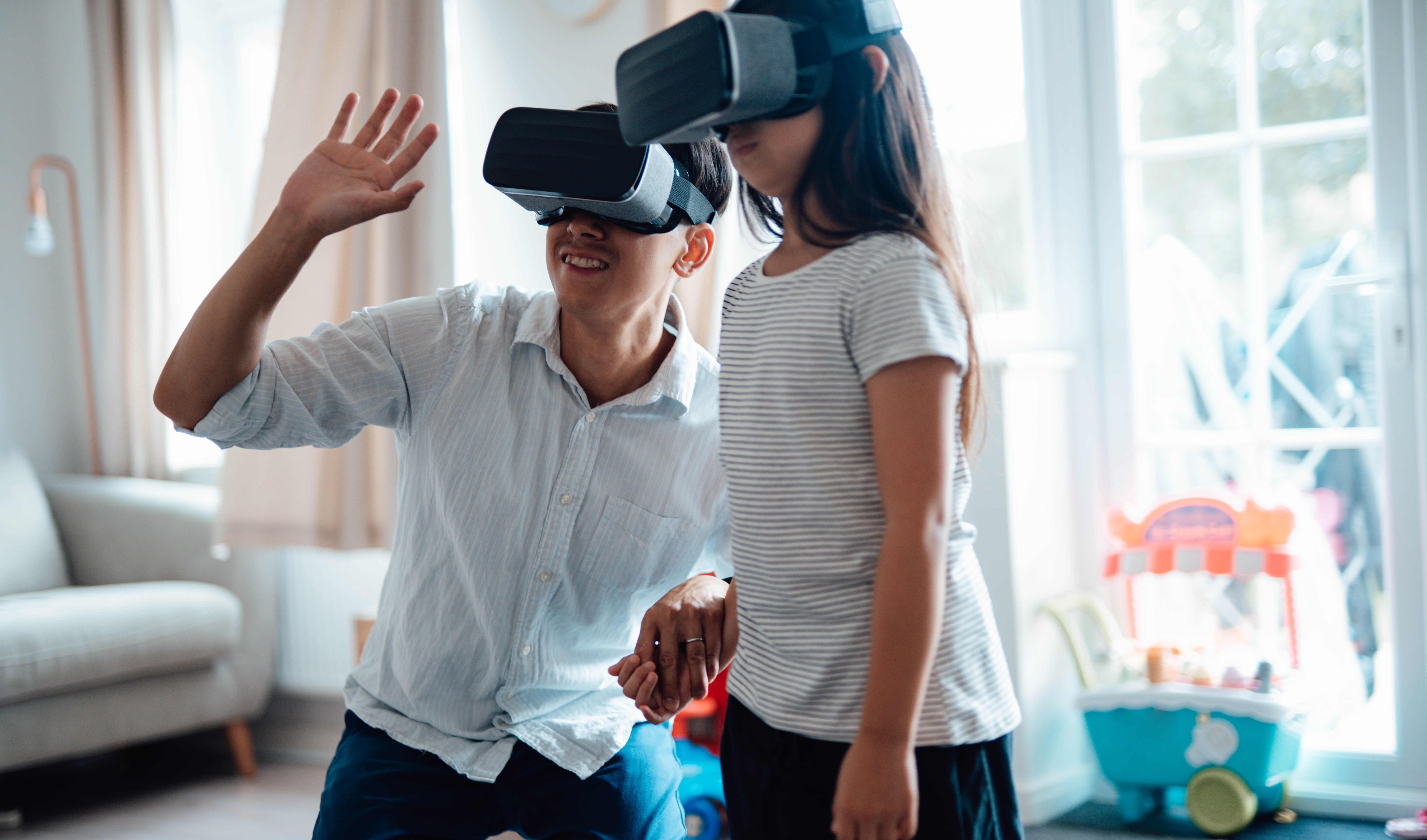 a father and a daughter playing with virtual reality goggles