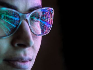 Electronic circuit board on computer monitor reflecting in glasses of a female engineer
