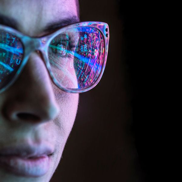 Electronic circuit board on computer monitor reflecting in glasses of a female engineer