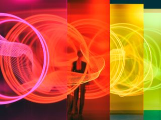Woman standing among glass walls illuminated by glowing rings