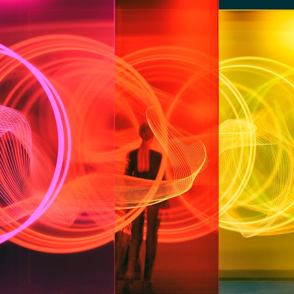 Woman standing among glass walls illuminated by glowing rings