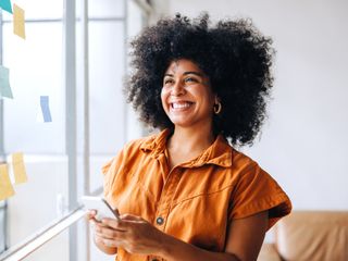 Woman smiling while using a smartphone in a creative office