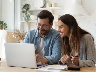 Man and woman smiling in front of a laptop