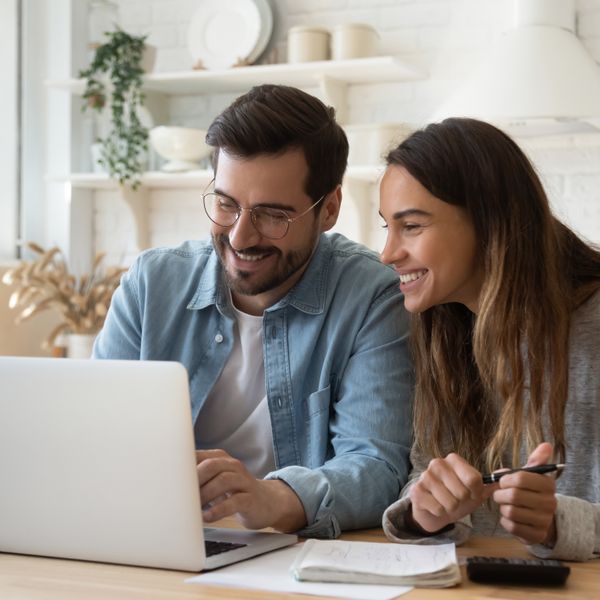 Man and woman smiling in front of a laptop