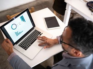 Man looking at data charts on a laptop