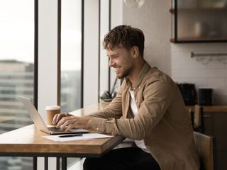 Man sitting while typing on a laptop