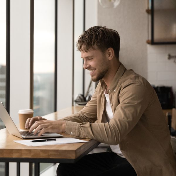 Man sitting while typing on a laptop