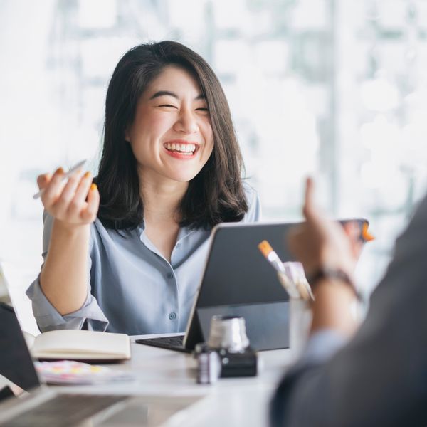 Woman smiling holding a pen in front of a tablet