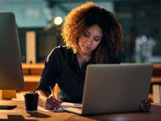 Woman writing in front of a computer