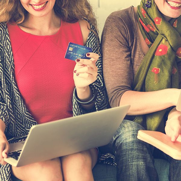 Girls sitting together holding tablets and credit card